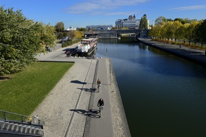 France, Paris (75), le canal de l'Ourcq dans le parc de la Villette et les anciens Grands Moulins de Pantin créées en 1884 réhabilités pour y réaliser un ensemble immobilier de bureauxen arrière plan
