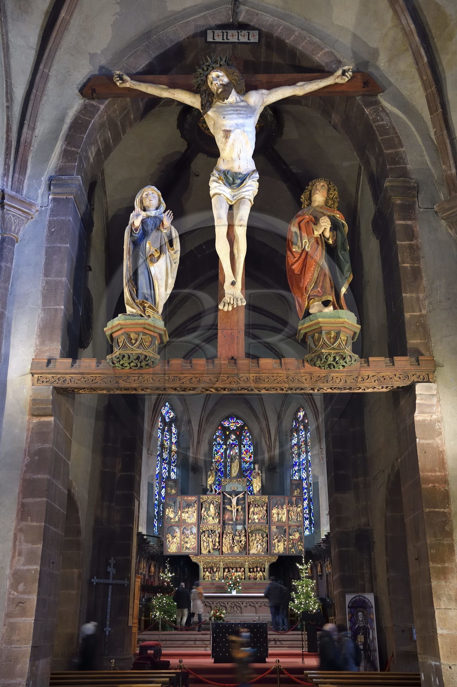 France, Haut-Rhin (68), Kaysersberg, église Sainte-Croix, Christ triomphant avec statues de la Vierge et de Saint-Jean du XVe siècle suspendus sous la voûte du transept et le choeur avec le retable de la Passion en bois de 1518 du sculpteur Jean Bongart en arrière plan