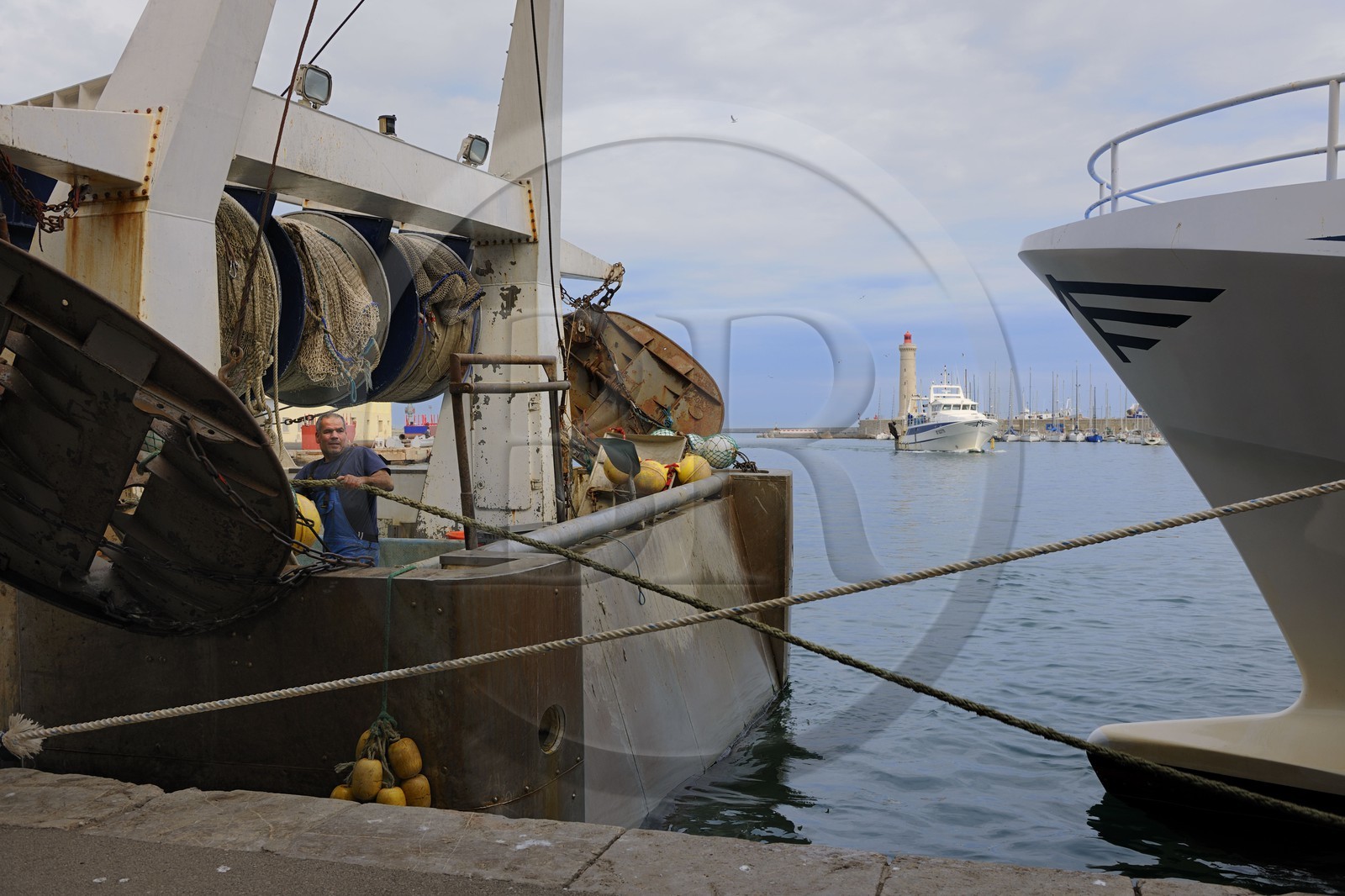 France, Herault, Sete, Vieux Port (Old harbour), docking activity on the wharf of the fish auction market and the lighthouse of the Mole St. Louis