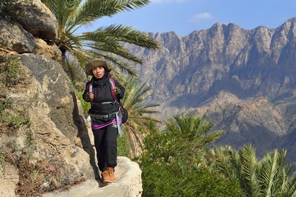 Sultanat d'Oman, Gouvernorat d'Al-Batina du Sud, Hajar occidental, Wadi Mistall, la randonneuse Badour Al Salhi suivant un falaj canal d'irrigation au dessus du village de Wakan (Wukan)