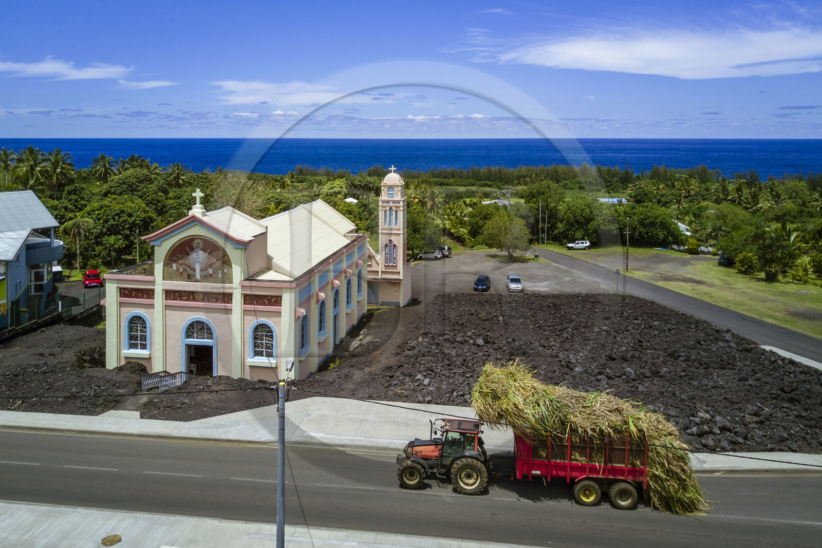 France, Ile de la Reunion, l'église Notre-Dame-des-Laves de Piton Sainte-Rose épargnée par la coulée de lave de 1977, un tracteur transporte un chargement de cannes à sucre vers l'usine (vue aérienne)