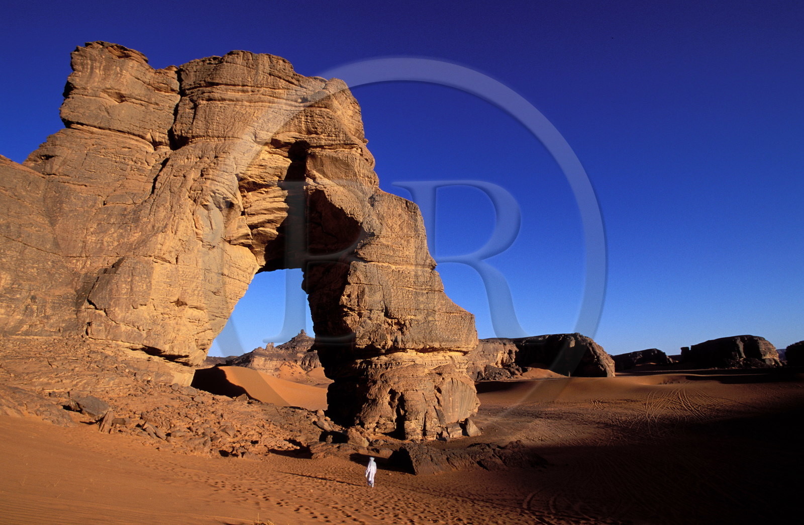 Libye, région du désert, Le Fezzan (Sahara), Touareg sous l'arche (en grès) de Afazedjar dans la Tadrart-Akakus