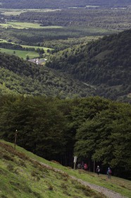 Spain, Basque Country, Navarra, pilgrims on the Camino de Santiago (the Way of St. James) going down towards Roncevaux and the Royal Collegiate Church of Roncesvalles in the background