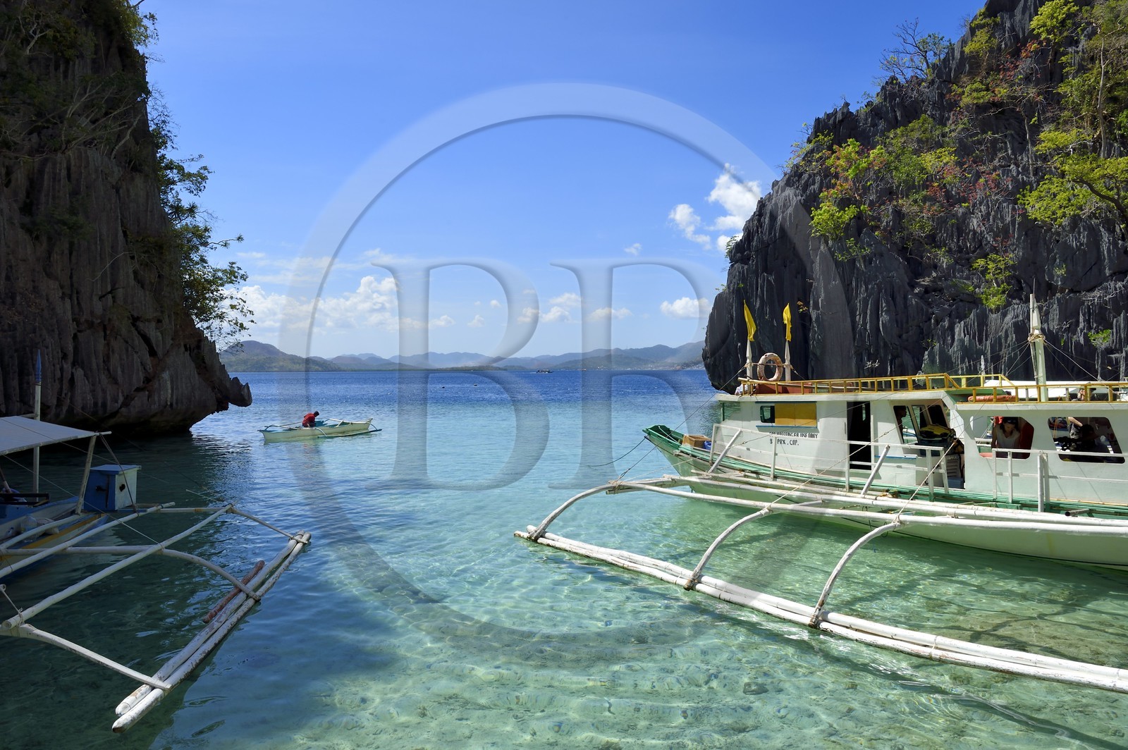 Philippines, Calamian Islands in northern Palawan, Coron Island Natural Biotic Area, Outrigger canoe under limestone rocks in a small cove