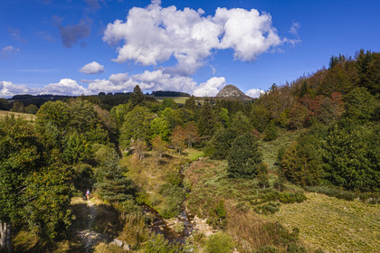France, Ardèche (07), parc naturel régional des Monts d'Ardèche, Massif du Mézenc, randonneuse sur le sentier du GR 7 à la jonction de la Loire à droite et du Riu l'Aigue Negre à gauche, le Mont Gerbier-de-Jonc (1551 m) où la Loire trouve sa source en arrière plan (vue aérienne)