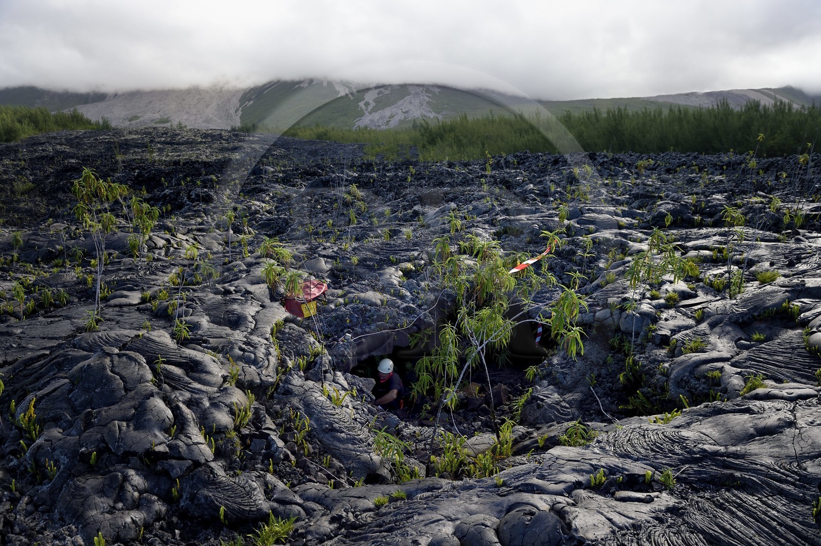 France, Reunion island (French overseas department), Piton de la Fournaise, listed as World Heritage by UNESCO volcano, the Grand Brule, recent lava flow and the volcano in the background, firefighter at the entrance of a lava tunnel during a rescue exercise