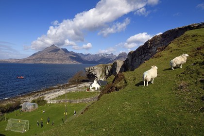 Royaume-Uni, Ecosse, région des Highlands, les Hébrides, Ile de Skye, village de Elgol sur les rives du Loch Scavaig au bout de la péninsule de Strathaird et le massif des Black Cuillin Mountains en arrière plan, enfants jouant au rounders dans le jardin de l'école
