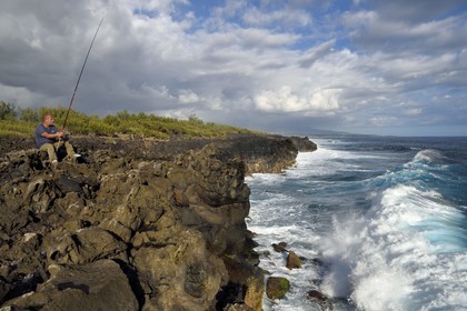 France, Reunion island (French overseas department), L'Etang Salé les Bains, the coast between Le Gouffre and the Etang du Gol (Gol Pond), black basaltic rocks of volcanic origin tormented by the ocean, angler
