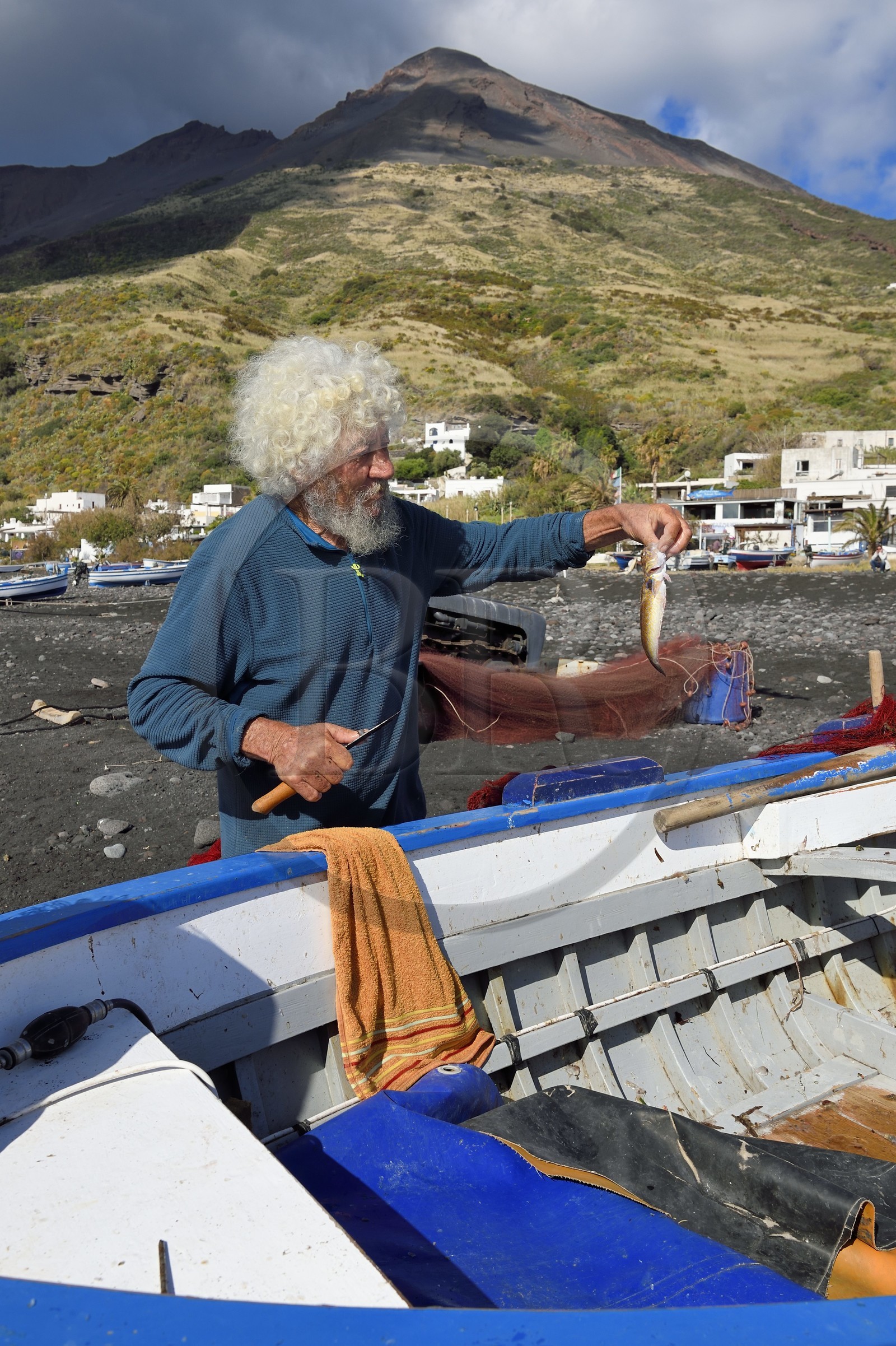 Italy, Sicily, Aeolian Islands, listed as World Heritage by UNESCO, Stromboli island, the fisherman Roberto Cusolito emptying his fish on the beach of Scari and the volcano Stromboli in the background