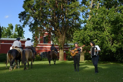 Argentine, province de Buenos Aires, San Antonio de Areco, groupe de gauchos à cheval devant l'estancia La Bamba de Areco et gauchos jouant des aires de Milongas sur leur guitare et accordéon