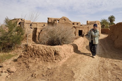 Iran, Province d'Ispahan, désert du Dasht-e Kavir, l'oasis d'Arousan dans la région de Khur et Biabanak, paysan rentrant du champ et maisons en terre crue