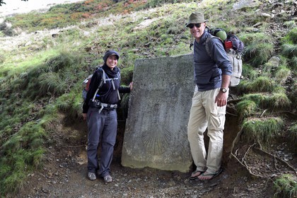 France, Pyrenees Atlantiques, Basque Country, Camino de Santiago (the Way of St. James) on the GR 65 between Saint Jean Pied de Port and Roncesvalles towards the Bentarte Pass, pilgrims in front of the stele indicating that Compostela is still 765 km