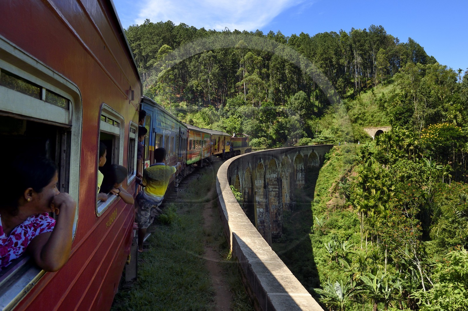 Sri Lanka, Uva Province, train on the railway track that goes through the tea growing hill country between Badulla and Ella, the Nine Arches bridge next to Ella, passengers hanging on the door
