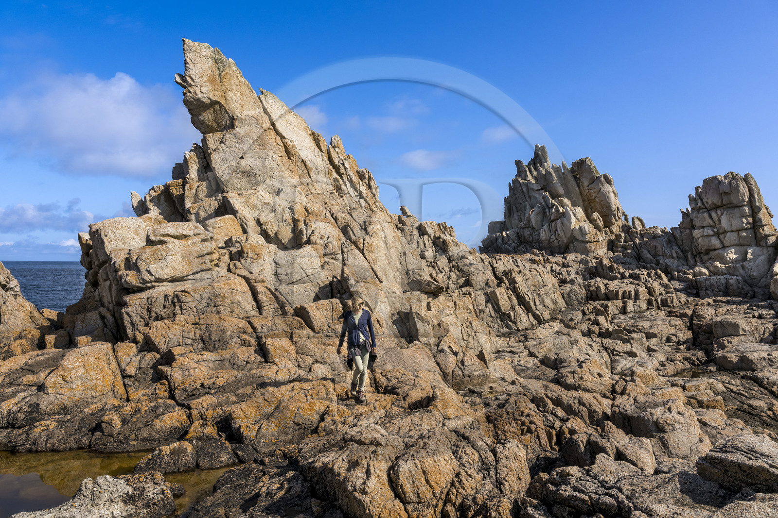 France, Finistère (29), Mer d'Iroise, Ile d'Ouessant, randonneuse dans les rochers façonnés par les tempêtes au pied du phare du Créac’h