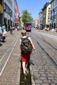 Allemagne, Bade-Wurtemberg, Fribourg en Brisgau, retour d'ecole dans la Kaiser-Joseph Strasse, un des Bächle qui sont des petits caniveaux ouverts qui bordent les trottoirs de la vieille ville
