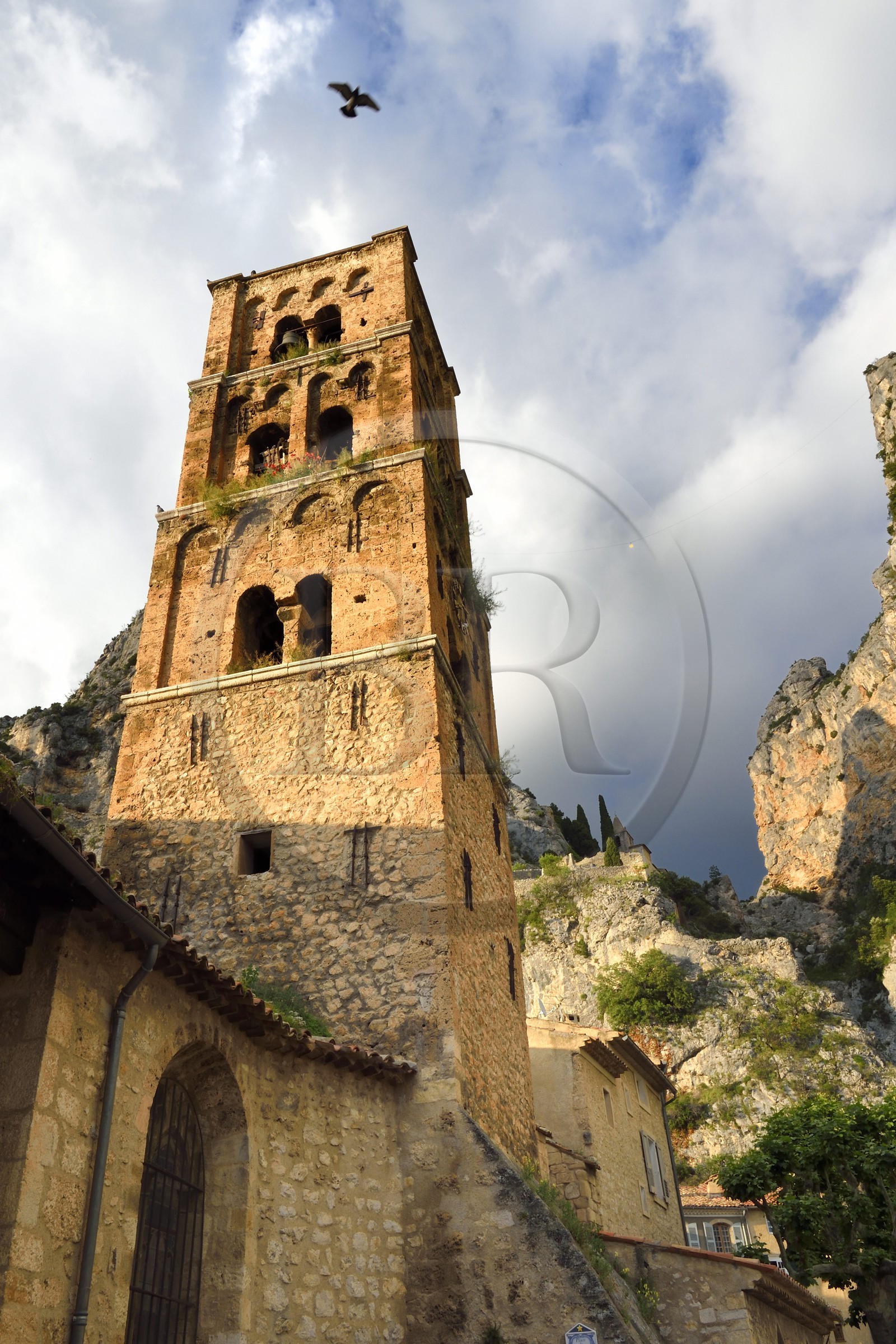 France, Alpes-de-Haute-Provence (04), Parc Naturel Régional du Verdon, Moustiers-Sainte-Marie, labellisé Les Plus Beaux Villages de France, l'église Notre-Dame-de-l'Assomption avec son clocher du XIIe siècle en tuff et l'Etoile de Moustier accrochée à une chaîne à plusieurs dizaines de mètres au-dessus du sol