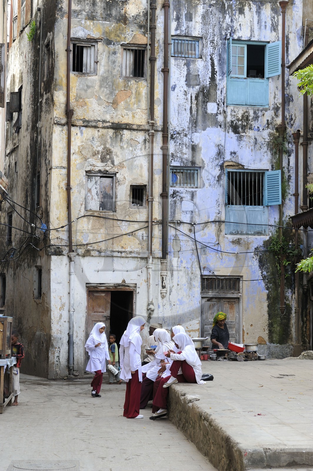 Tanzanie, archipel de Zanzibar, île de Unguja (Zanzibar), ville de Zanzibar, quartier Stone Town, classé Patrimoine Mondial de l' UNESCO, jeunes écolières devant des facades de maisons décrépies dans une ruelle de la vieille ville dans le quartier de Shangani