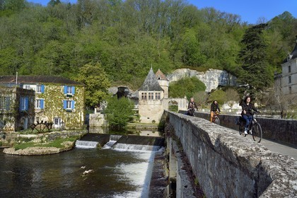 France, Dordogne (24), Brantôme, Pont Coudé sur la Dronne et le Moulin de L'Abbaye à gauche, ancien moulin du XVIe siècle transformé en Hotel****-Restaurant de charme, le pavillon Renaissance et la tour qui formaient la porte fortifiée en arrière plan, cyclistes sur la véloroute la Flow Vélo
