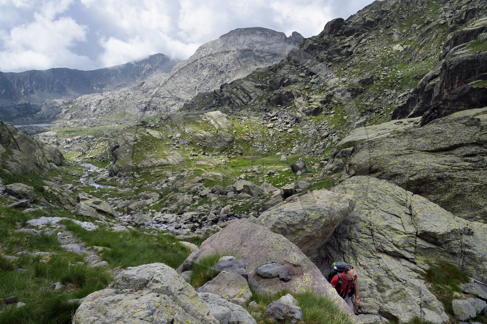 France, Alpes-Maritimes (06), parc national du Mercantour, randonneur passant un seuil sur le sentier de randonnée GR 52, la Vallée des Merveilles parsemée de milliers de gravures rupestres de l'Age de bronze et la Paroi vitrifiée en arrière plan