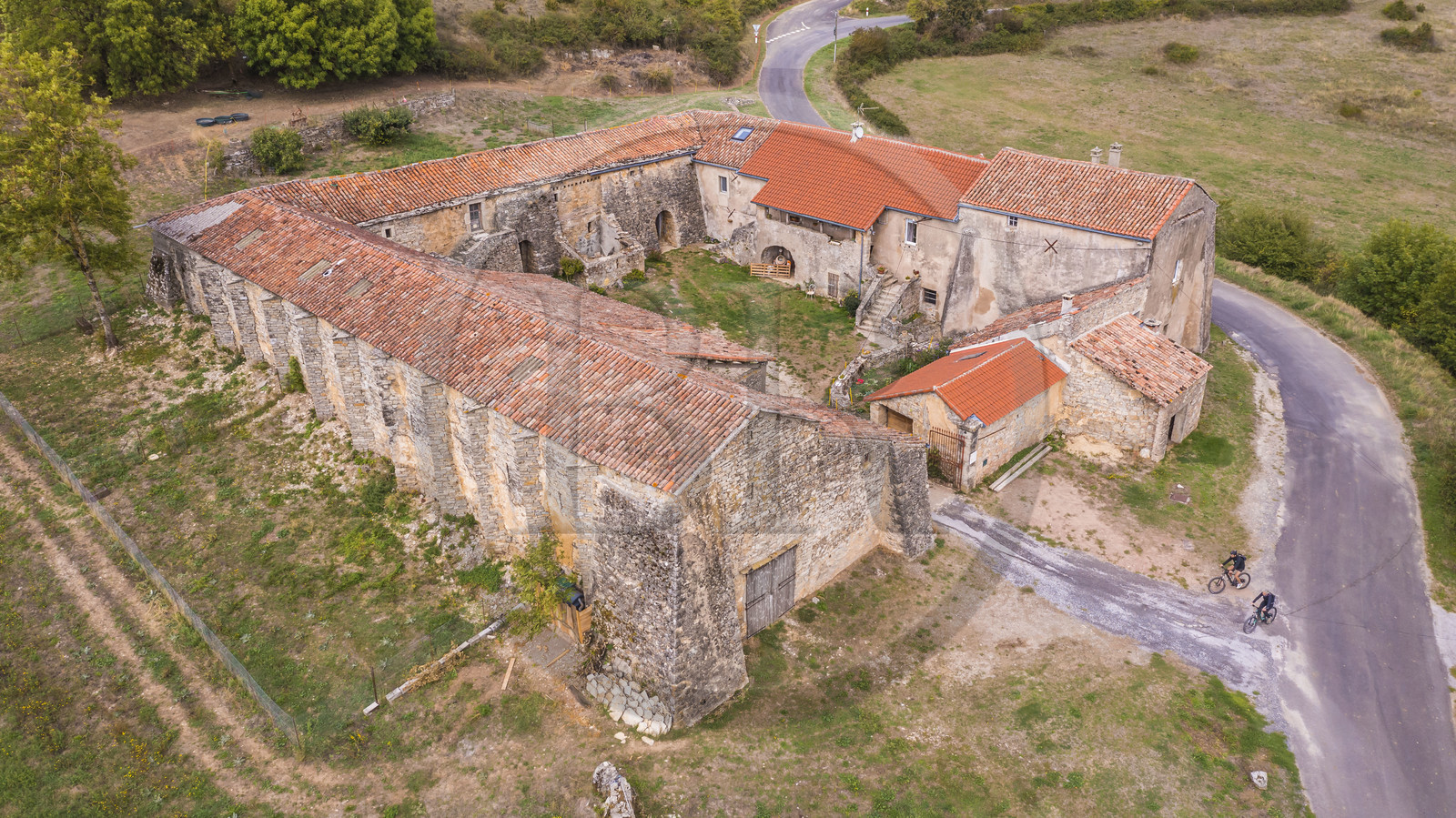 France, Aveyron, Grands-Causses Regional Nature Park, cyclists on the Brebis Cyclette tourist cycle route in the Pays de Roquefort, Mascourbe Farm which belonged to the Commandery of the Hospitallers of St. John of Jerusalem (aerial view)
