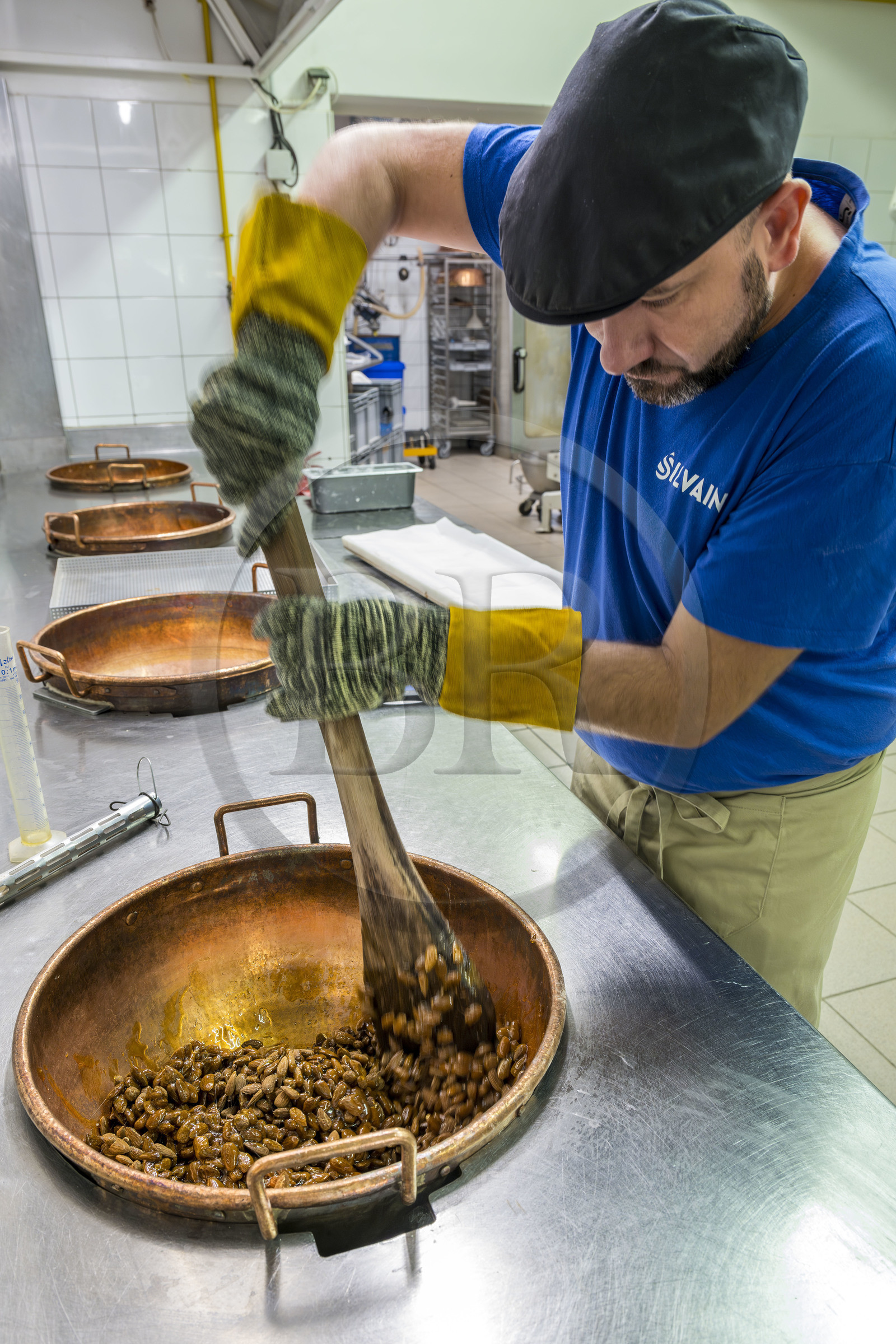 France, Vaucluse (84), Saint Didier, dans l'atelier de fabrication des Nougats Silvain, paysans nougatiers, Charles-Henri Bagnol confectionne une plaque de nougat noir, mélange des amandons grillés et de la base de miel caramélisé