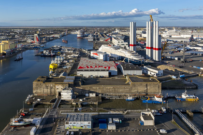 France, Loire Atlantique, Saint Nazaire, the East lock and the fortified lock of the former German submarine base built during the last world war in the foreground and the construction site of the luxury super-yacht Ritz-Carlton Luminara in the Joubert dry dock, the wind turbine towers  on the right are stored before embarkation, the 333m MSC World America cruise ship built by Chantiers de l'Atlantique in the background (aerial view)