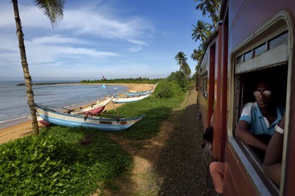 Sri Lanka, Province de l'Ouest, train de Colombo à Galle, bateaux de peche sur la plage en bordure de la voie ferrée