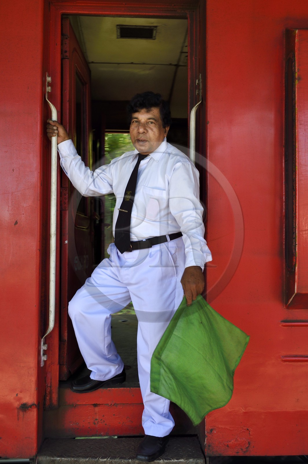 Sri Lanka, Uva Province, the popular scenic train ride through the tea growing hill country between Badulla and Ella, train conductor with the green flag giving the starting signal