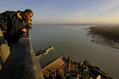 France, Manche, Mont Saint Michel, listed as World Heritage by UNESCO, Mr Antoine Bacchiarotti looking at the Apse and the bay from the spire at dawn