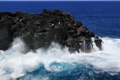 France, Ile de la Reunion, côte sud, Saint-Philippe, le Cap Méchant est situé le long d'une côte déchiquetée de roche volcanique frappée par la houle et typique de la région appelée Sud sauvage, pêcheur sur un rocher