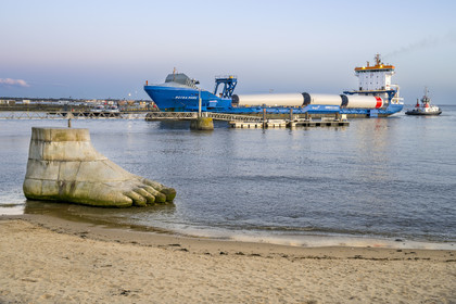 France, Loire-Atlantique (44), Estuaire de la Loire, Saint-Nazaire, collection d'art contemporain à ciel ouvert Estuaire, une des trois sculptures monumentales en béton Le pied, le pull et le système digestif réalisée par les artistes Daniel Bewar et Gregory Gicquel en bordure du Quai de la Jetée, le General Cargo Rotra Mare transportant des sections des mats d'éoliennes en arrière plan
