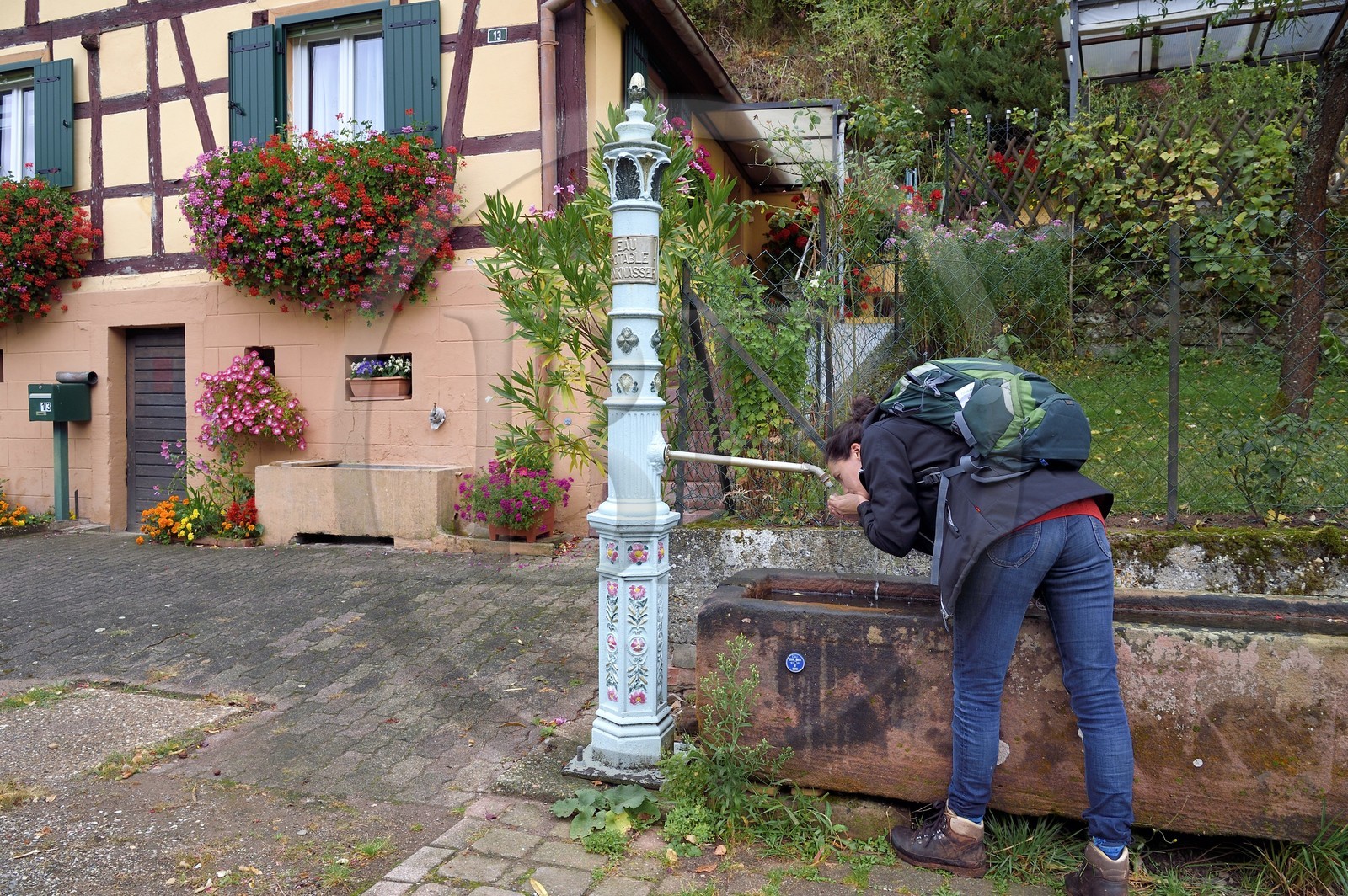 France, Bas-Rhin (67), Parc naturel régional des Vosges du Nord, Niedersteinbach, randonneuse buvant à une des nombreuses fontaines du village