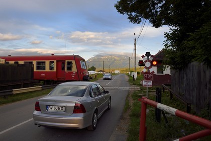 Romania, Transylvania, Zarnesti, train at the railway crossing and the Fagaras Mountains in the Southern Carpathians