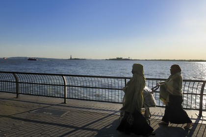 Etats-Unis, New York, Manhattan, pointe Sud, femmes voilée en promenade sur Battery Park et la Statue de la Liberté en arrière plan