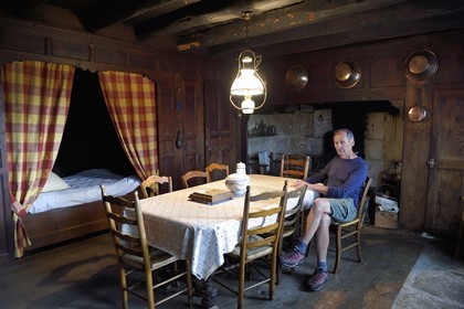 France, Cantal (15), Parc naturel régional de l'Aubrac, hameau de Le Laussier à Lieutades, lit-clos à rideau dans la salle commune, le guide naturaliste et aquarelliste Thierry Ballay dans la maison de famille