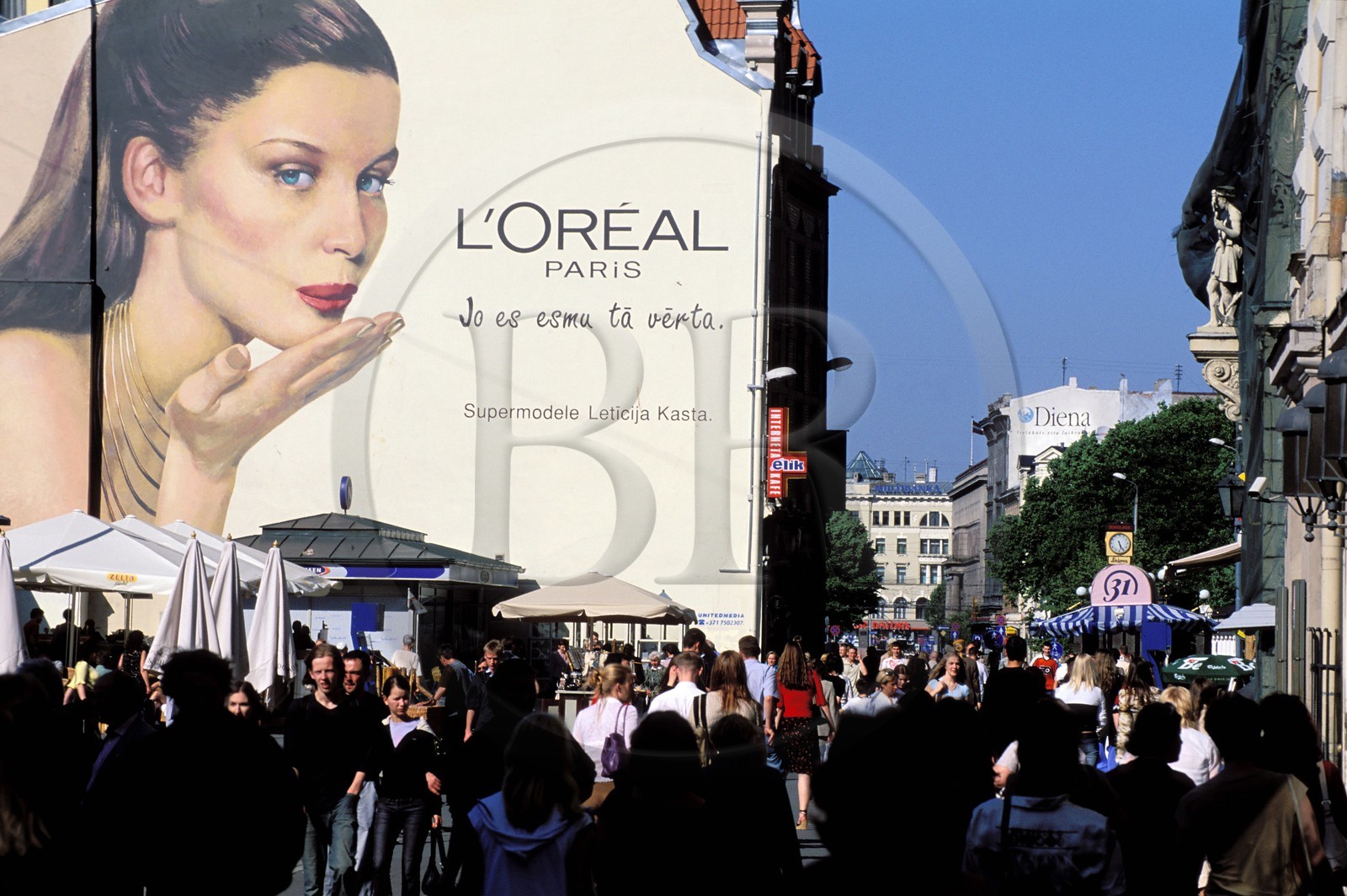 Lettonie (Pays Baltes), Riga, piétons sur la place jouxtant rue Kalku peinture murale publicitaire avec le top model Laetitia Casta (L'Oréal)