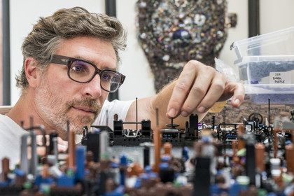 France, Cote d'Or, Dijon, Artist Aymeric Gillet, aka M'Brick, in his studio filled with crates of multicolored Lego used to create giant pixelated paintings inspired by pop culture