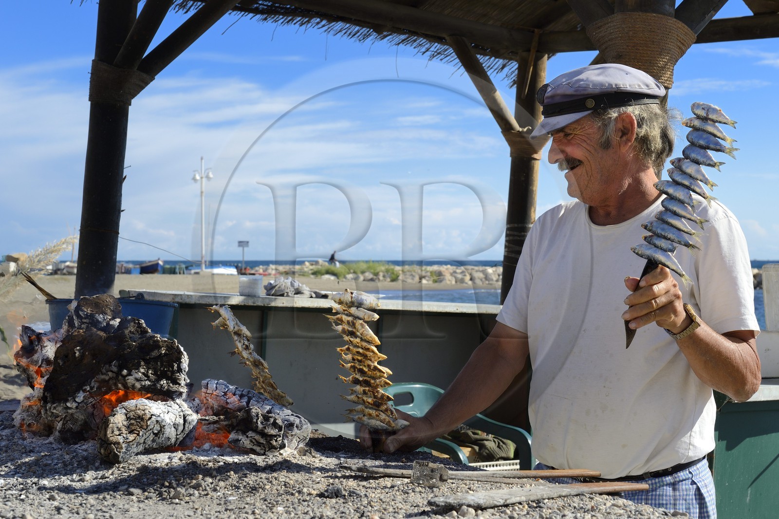 Spain, Andalusia, Malaga, fishing district of Pedregalejo, fisherman and grilled sardines
