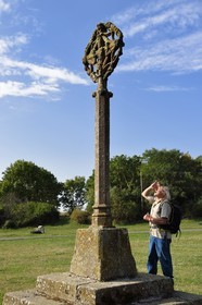 France, Cantal, Parc Naturel Régional des Volcans d'Auvergne (regional nature park of Auvergne volcanoes), hiker on the Way of St. James to Santiago de Compostela by Via Arverna, Chalinargues, the 15th century granite Cross of Mons, on this side we can see the Virgin surrounded by angels, kneeling people and saints, on the other Christ