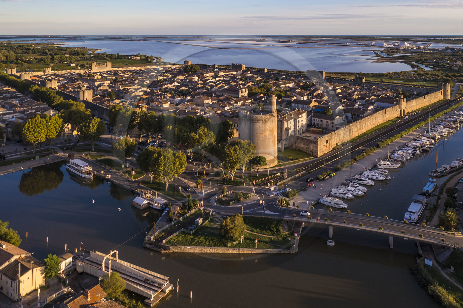 France, Gard (30), Aigues-Mortes, la ville médiévale entourée par ses remparts, la Tour de Constance et le port du canal du Rhône à Sète au premier plan, les marais salants (Salins du Midi) en arrière plan (vue aérienne)