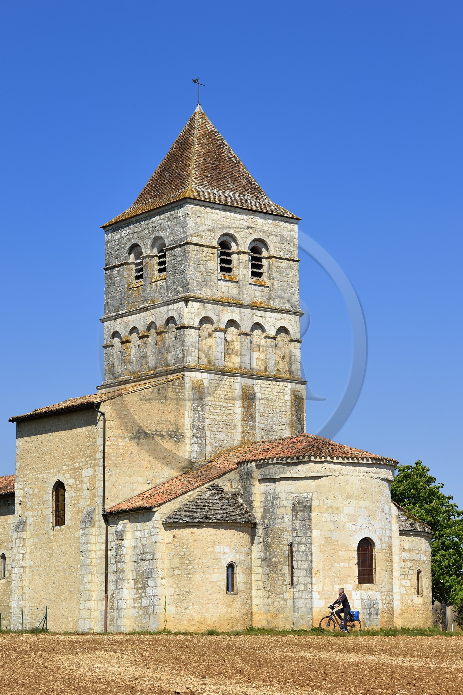 France, Dordogne, Périgord Vert, Javerlhac-et-la-Chapelle-Saint-Robert, cyclist traveling along the Flow Vélo cycle route in front of the 12th century Romanesque church of La Chapelle-Saint-Robert, church of the former priory founded by a disciple of the first abbot of La Chaise-Dieu Robert de Turlande