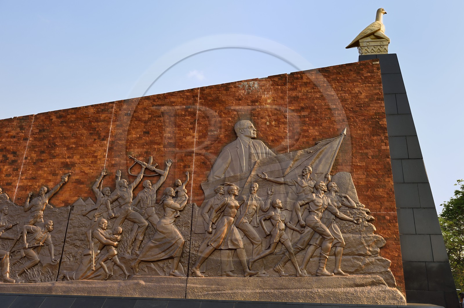 Zimbabwe, Harare, burial ground and national monument to commemorate Patriotic Front guerrillas killed during the Rhodesian Bush War, wall carrying murals depicting the history of Zimbabwe, here the independence movement under national hero Robert Mugabe and the stone-carved Zimbabwe Bird on the top