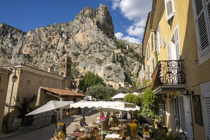 France, Alpes-de-Haute-Provence (04), Parc Naturel Régional du Verdon, Moustiers-Sainte-Marie, labellisé Les Plus Beaux Villages de France, l'église Notre-Dame-de-l'Assomption avec son clocher du XIIe siècle en tuff et l'Etoile de Moustier accrochée à une chaîne à plusieurs dizaines de mètres au-dessus du sol, la chapelle Notre-Dame de Beauvoir en arrière plan dans la falaise