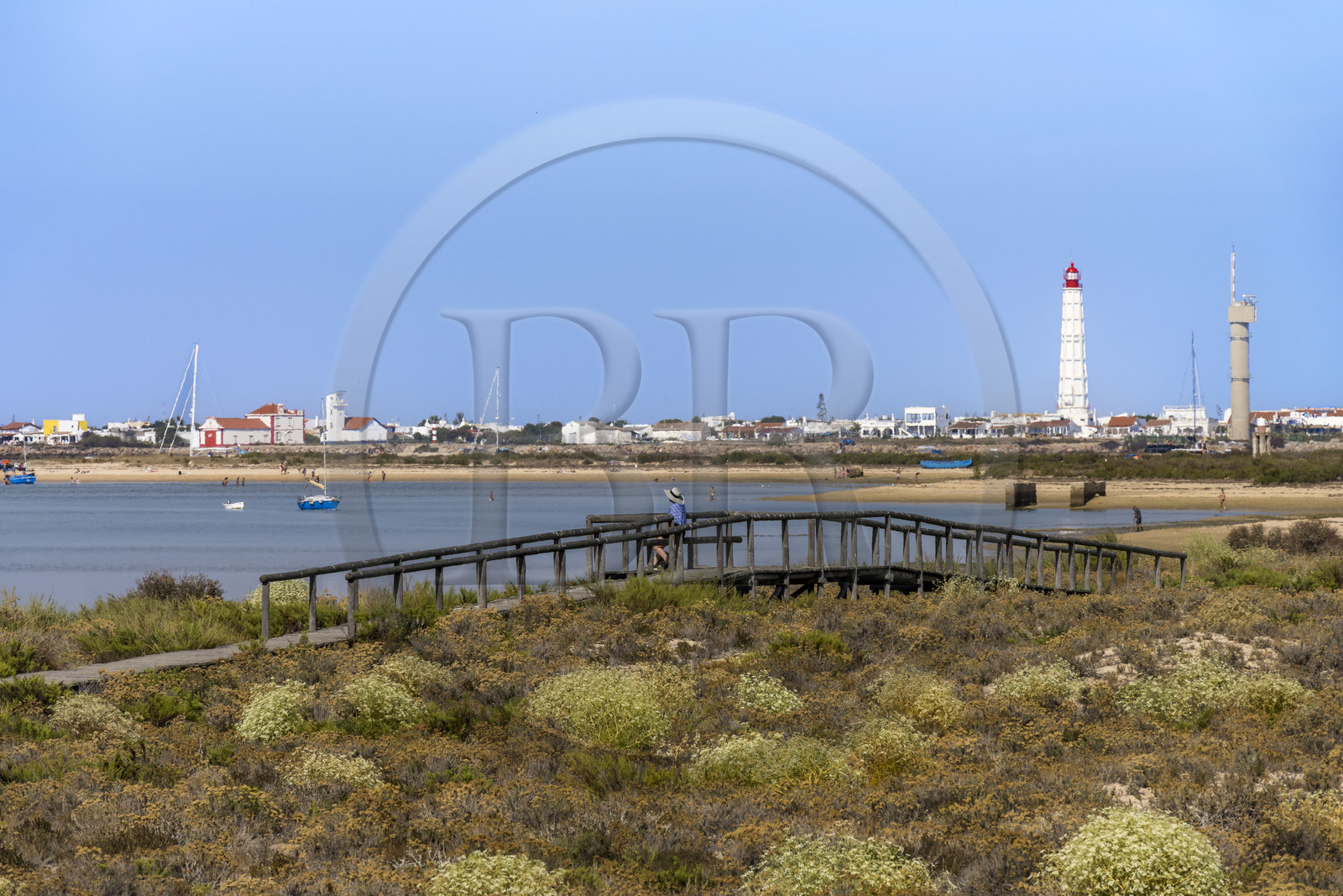 Portugal, Algarve, Ria Formosa Natural Park, Faro, wooden plank path on Island of Barreta or Deserta (Ilha da Barretta or Deserta), the lighthouse of Ilha do Farol part of  Ilha da Culatra in the background