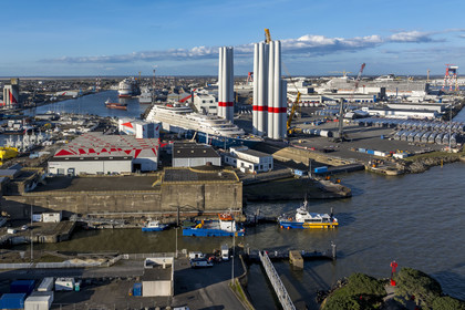 France, Loire Atlantique, Saint Nazaire, the East lock and the fortified lock of the former German submarine base built during the last world war in the foreground and the construction site of the luxury super-yacht Ritz-Carlton Luminara in the Joubert dry dock, the wind turbine towers  on the right are stored before embarkation, the 333m MSC World America cruise ship built by Chantiers de l'Atlantique in the background (aerial view)