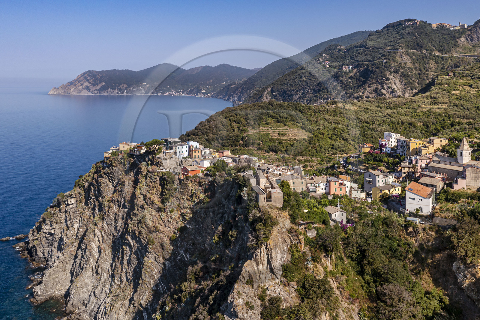 Italy, Liguria, Cinque Terre National Park listed as World Heritage by UNESCO, the village of Corniglia located at the top of a promontory overlooking the Mediterranean Sea at an altitude of about 100 m, the coast towards Monterosso in the background (aerial view)