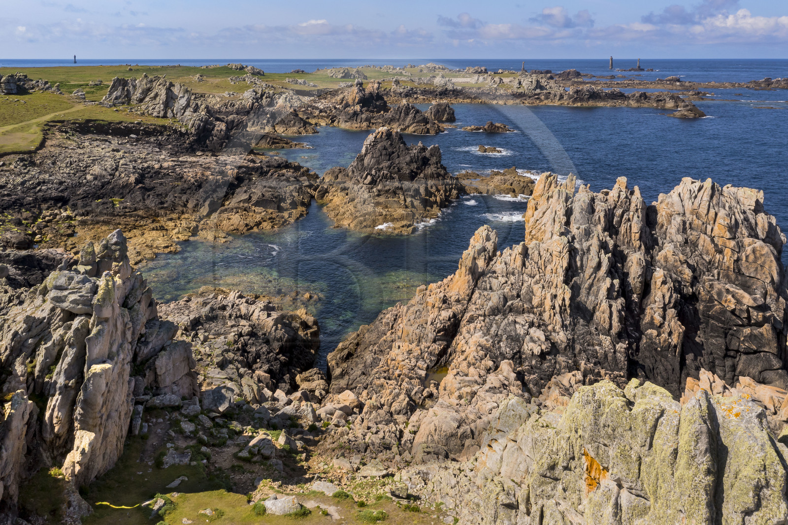 France, Finistère (29), Mer d'Iroise, Ile d'Ouessant, rochers façonnés par les tempêtes au pied du phare du Créac’h, le phare de Nividic sur la Pointe de Pern en arrière plan (vue aérienne)
