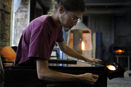 France, Moselle, Meisenthal, glassblower Thibaut at the Centre international d'Art verrier (CIAV) (international glass centre) is using a wooden tool called mailloche to round up the glass and make a christmas bowl made of glass which is even