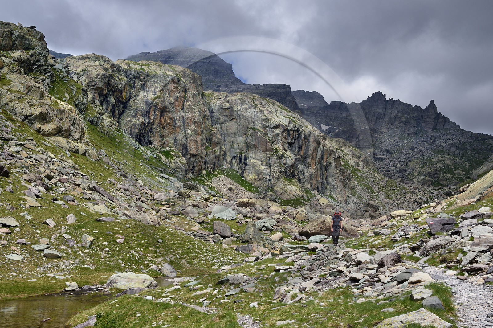 France, Alpes-Maritimes (06), parc national du Mercantour, Vallée des Merveilles parsemée de milliers de gravures rupestres de l'Age de bronze, randonneur sur le sentier de randonnée GR 52 au lac des Merveilles en contrebas de la Baisse de Valmasque et le Mont du Grand Capelet (2915m) en arrière plan à gauche
