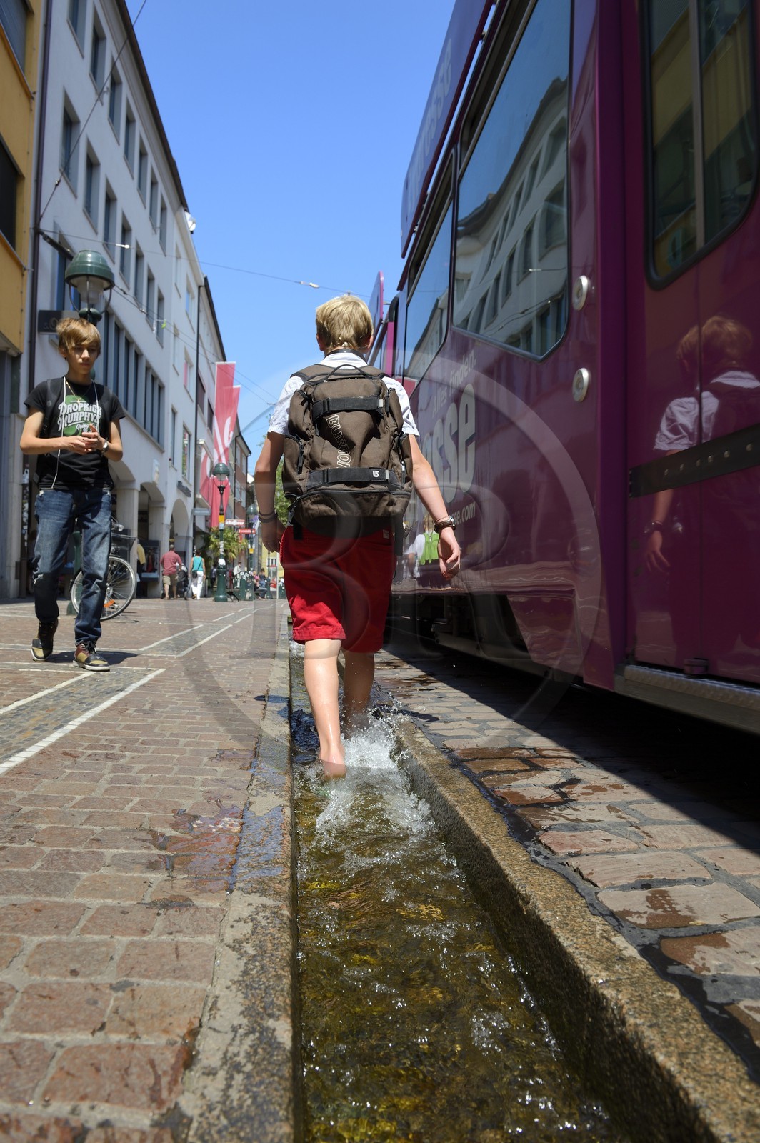 Allemagne, Bade-Wurtemberg, Fribourg en Brisgau, retour d'ecole dans la Kaiser-Joseph Strasse, un des Bächle qui sont des petits caniveaux ouverts qui bordent les trottoirs de la vieille ville